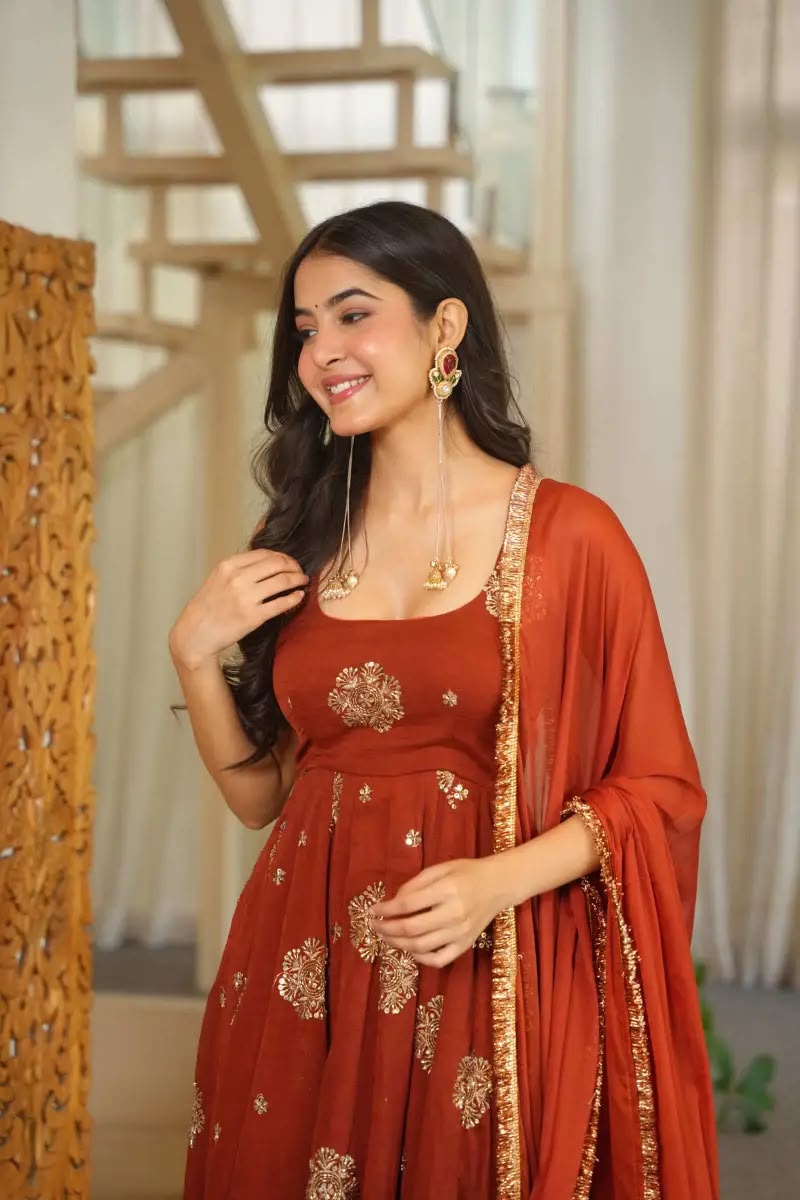 Model wearing silk anarkali suit set with heavy embroidery in rust color