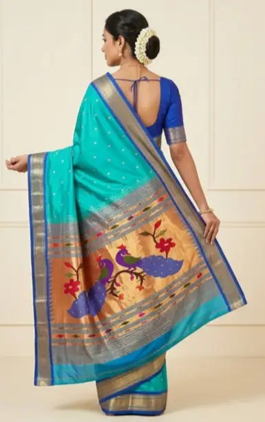 Woman in turquoise blue silk saree with gold zari border and peacock motif pallu