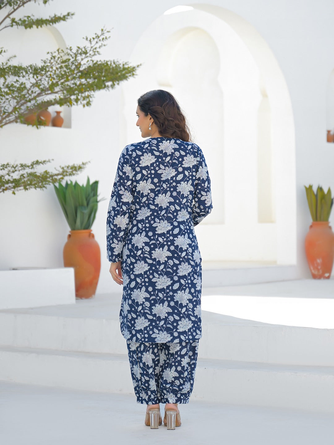 Woman wearing a blue floral print Indian ethnic kurta and matching trousers set.