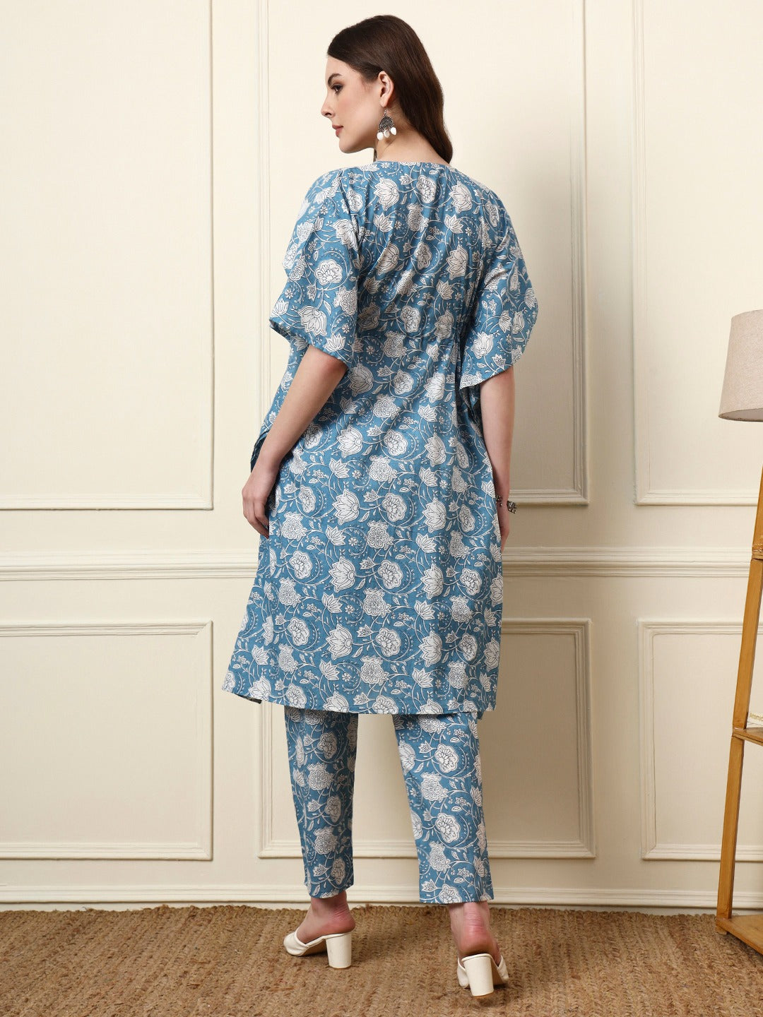 Woman wearing a blue floral print Indian ethnic kurta and matching trousers set.