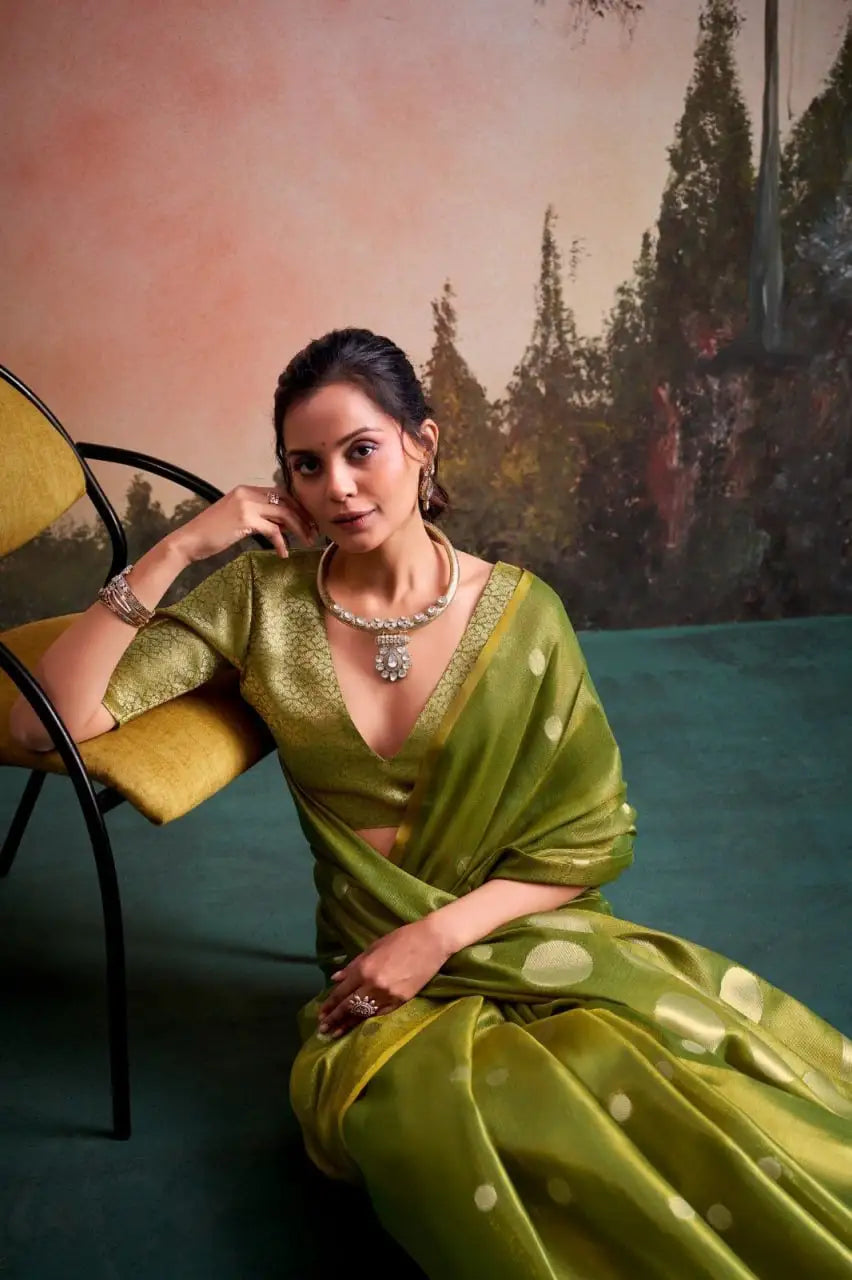 Woman wearing an elegant green silk saree with gold polka dots and traditional silver jewelry.
