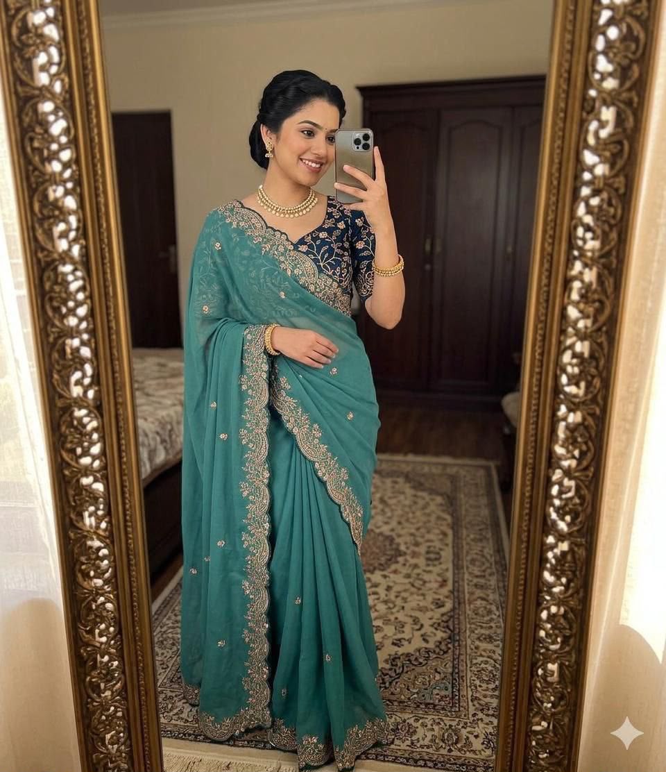 Woman wearing a teal blue saree with gold embroidery and a navy blue blouse.