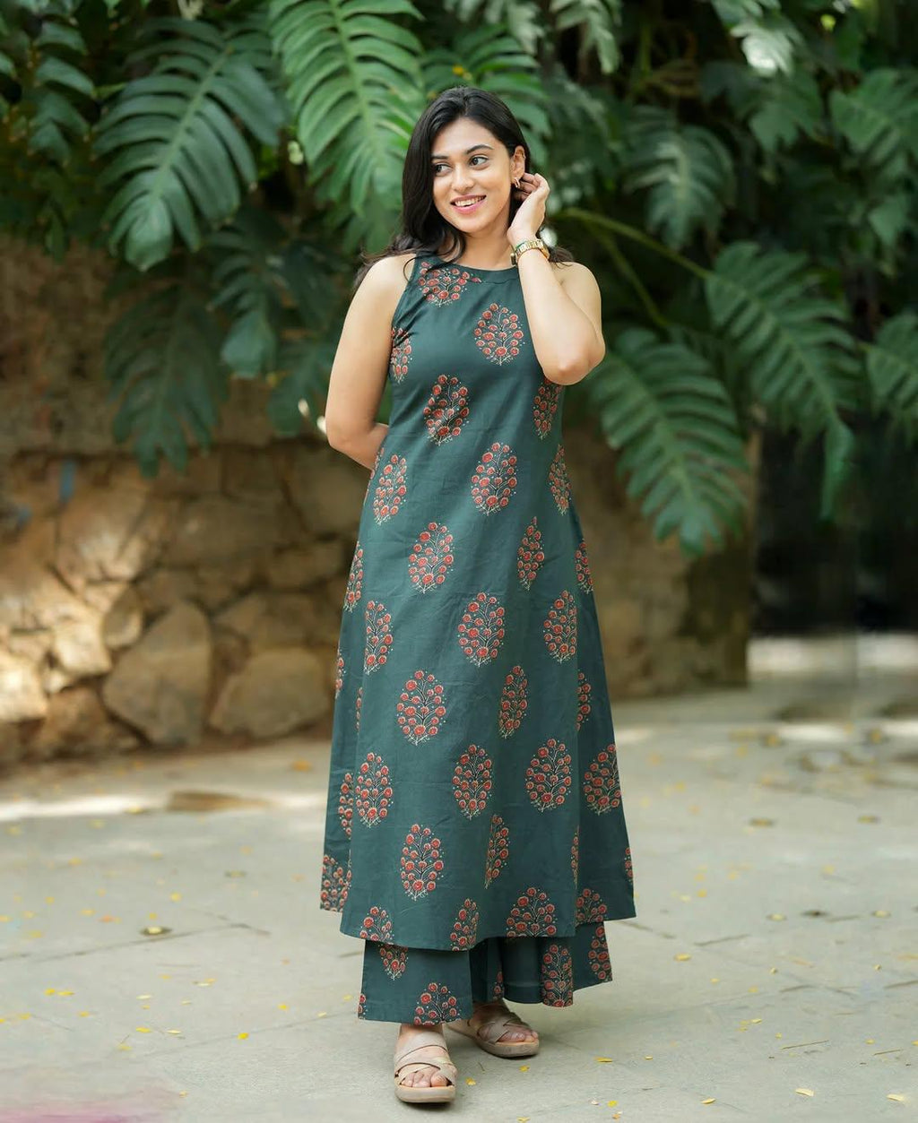 Woman wearing a dark green floral print ethnic dress and matching trousers.